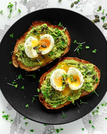 Healthy avocado and egg toasts with pumpkin and sesame seeds, sprinkled with cress salad