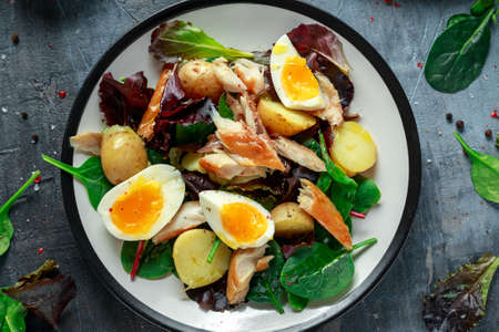 Warm Smoked Mackerel Salad with new potato, eggs, green lettuce mix in a plate.の写真素材