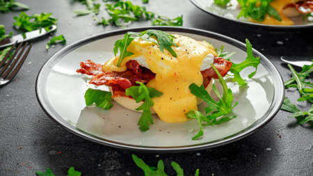 Eggs Benedict on english muffin with crispy bacon, wild rocket salad and hollandaise sauce.