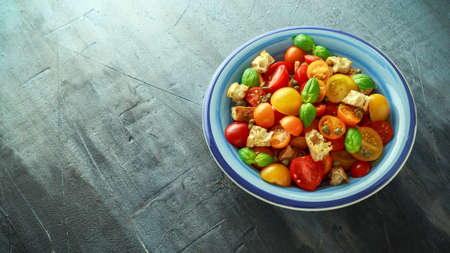 Panzanella Tomato salad with red, yellow, orange cherry tomatoes, capers, basil and ciabatta croutons. summer healthy food.の写真素材