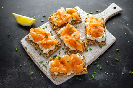 Homemade Crispbread toast with Smoked Salmon and soft chees, chives on white boardの写真素材