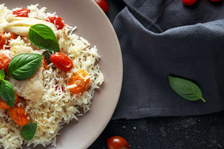 Steamed cod fish with rice and cherry mix tomatoes and basil herbs in a plateの写真素材