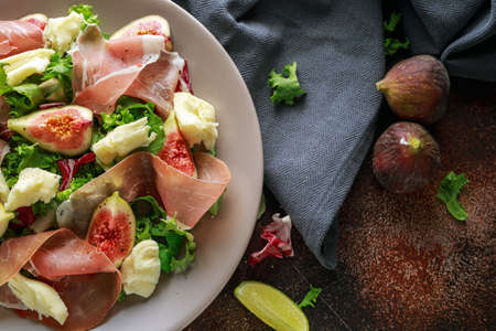 Fresh figs salad with prosciutto, green mix and cheese in a plateの写真素材