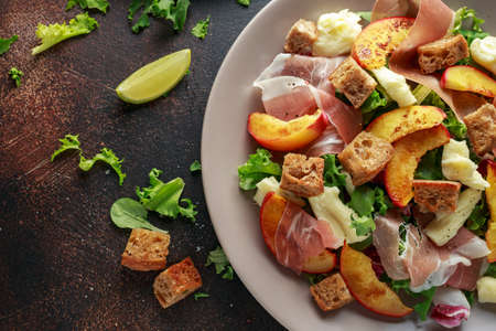 Fresh grilled peach salad with green mix, cheese, prosciutto and croutonの写真素材