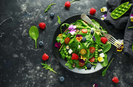 Summer salad with edible flowers, spinach, blueberries, raspberry, sweet peas, cherry tomatos and feta cheese.の写真素材