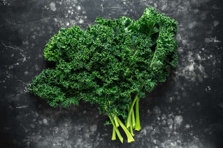 Raw organic freshly picked green curly kale on black table