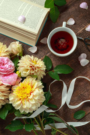 Summer theme tea with freshly picked flower bouquet: dahlias and roses on wooden table. Rustic styleの写真素材