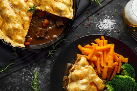 Traditional English beef beer, ale pie served with carrots and broccoliの写真素材