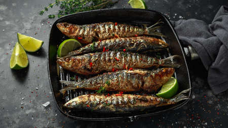 Grilled sardines with thyme, chili and lime wedges on cast iron skilletの写真素材