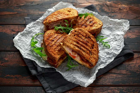 grilled sandwich with turkey, bacon, tomato and cheese on rustic wooden backgroundの写真素材