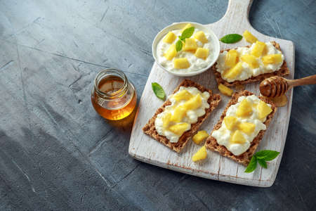 Homemade Crispbread toast with Cottage Cheese, Pineapple and honey on white wooden board.の写真素材