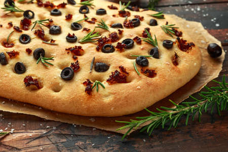 Homemade Italian focaccia with sun dried tomatoes, black olives and rosemaryの写真素材