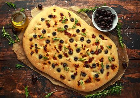 Homemade Italian focaccia with sun dried tomatoes, black olives and rosemaryの写真素材