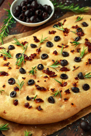 Homemade Italian focaccia with sun dried tomatoes, black olives and rosemaryの写真素材