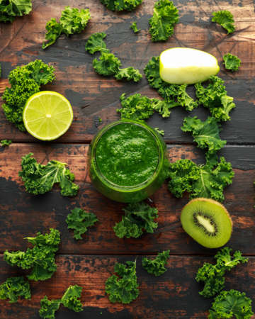 Green smoothies with kale, kiwi, apple and lime on wooden tableの写真素材