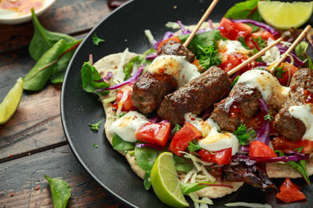 Lamb mint kebabs with flatbread, mix of vegetables, lime and greek yoghurt chilli sauceの写真素材