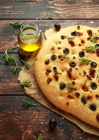 Homemade Italian focaccia with sun dried tomatoes, black olives and rosemaryの写真素材