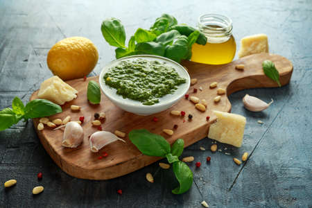Green Basil Pesto with parmesan cheese, pine nuts, garlic and lemon on wooden boardの写真素材