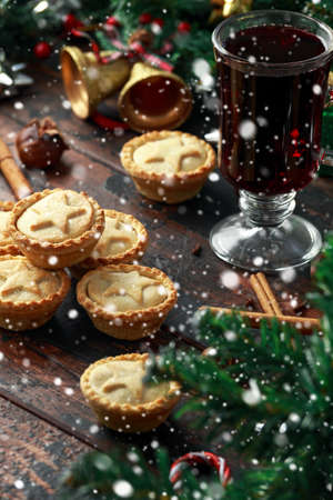 British Christmas mince pies with decoration, gifts, snow, green tree branch on wooden rustic tableの写真素材