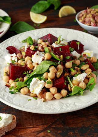 Healthy Beet Salad with chickpeas, pistachios nuts, feta and melted cheese toast on rustic wooden backgroundの写真素材