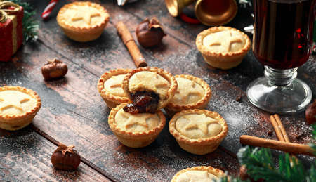 British Christmas mince pies with decoration, gifts, green tree branch on wooden rustic table
