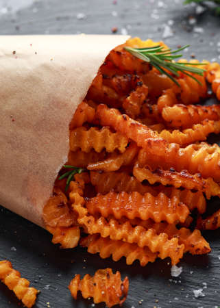 Baked butternut squash fries with sea salt and rosemary in paper cone. Pumpkin chips