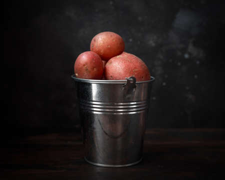 Raw red potato in metal bucket on windows light. rustic styleの写真素材