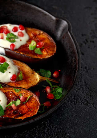 Grilled eggplants with yogurt sauce, pomegranate seeds, parsley and green onion in cast iron vintage pan.の写真素材