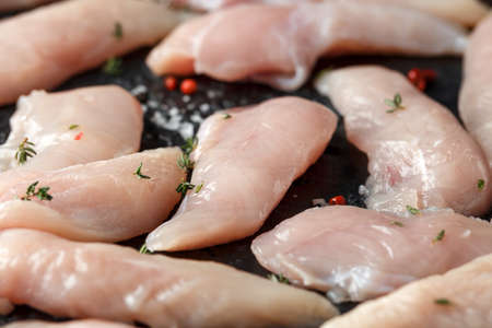 Raw chicken breast mini fillets in rastic cast iron skillet, frying pan with herbs and sea saltの写真素材