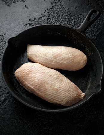 Raw duck brest fillets on rustic cast iron pan, skilletの写真素材