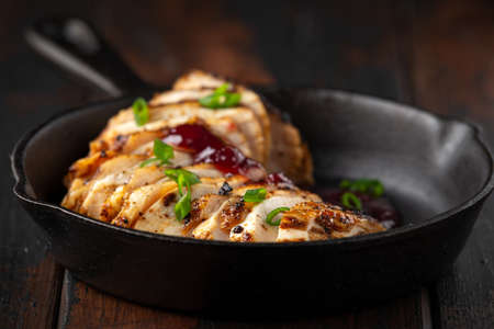 Grilled sliced chicken breast with cranberry sauce in mini cast iron frying panの写真素材