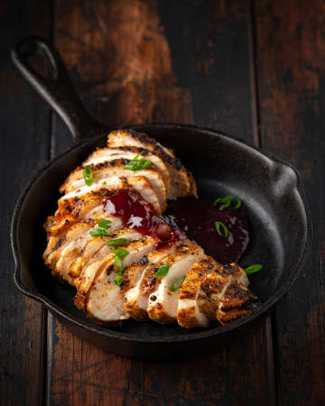 Grilled sliced chicken breast with cranberry sauce in mini cast iron frying pan.の写真素材