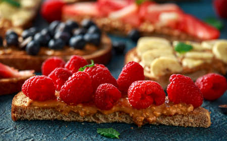 Peanut butter sandwiches with fresh strawberry, blueberry, raspberry and banana whole meal toasts.