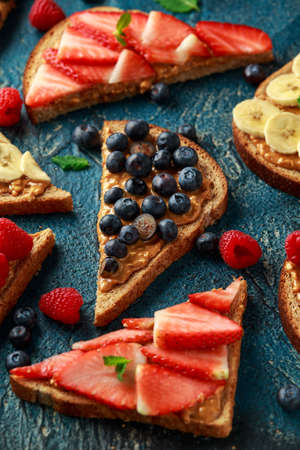 Peanut butter sandwiches with fresh strawberry, blueberry, raspberry and banana whole meal toasts.の写真素材