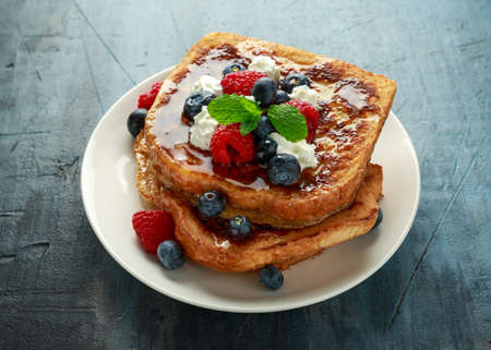 French cinnamon toast with blueberries, raspberries, maple syrup and coffee. morning breakfastの写真素材