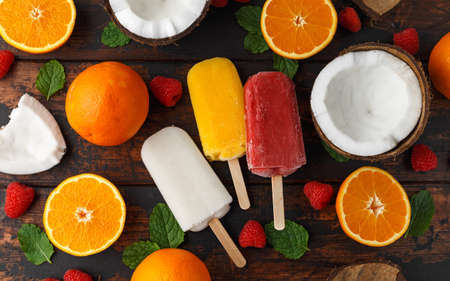 Homemade Coconut, Orange, raspberry ice cream, ice lolly, on wooden table. Summer food.