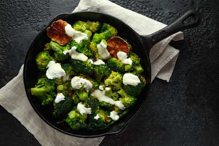 Fried broccoli with garlic yogurt and lemon zest in cast iron skillet, frying panの写真素材