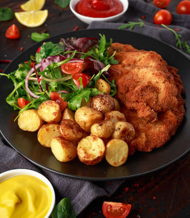 Homemade breaded pork schnitzel with roast potato and vegetablesの写真素材