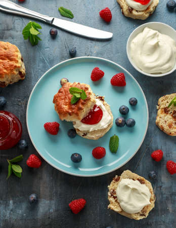 Classic English scones with clotted cream, strawberries jam and other fruit.の写真素材