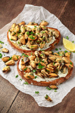Homemade Mussels on grilled bruschetta, toast with soft cheese and herbs
