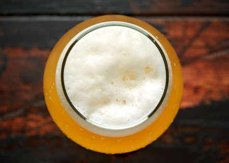 Glass of chilled unfiltered beer with on wooden tableの写真素材