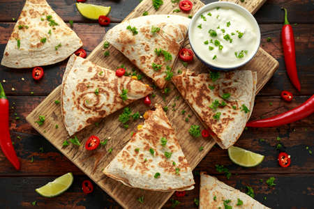 Mexican quesadilla with chicken, corn, black beans, cheese, vegetables, lime and yogurt sauce on...