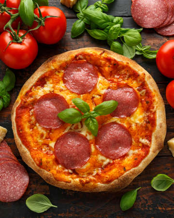 Homemade Pepperoni, Salami Pizza with basil, tomatoes, cheese on wooden table. ready to eat.の写真素材