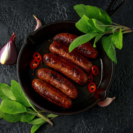 Butcher made sage and onion sausages baked in cast iron skillet, pan.の写真素材