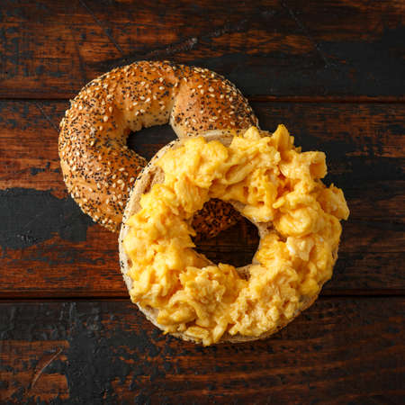 Bagels breakfast sandwich with scrambled eggs on wooden tableの写真素材