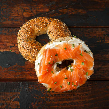 Bagels breakfast sandwich with Cream cheese and salmon on wooden tableの写真素材