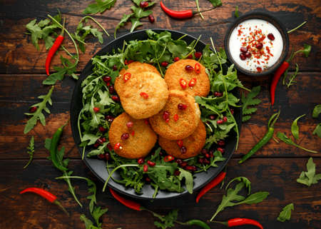 Thai food spicy fish cakes served with pomegranate seeds and wild rocket, arugula salad.