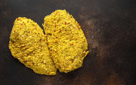 Breaded ready to cook fresh raw chicken Kievs on dark background