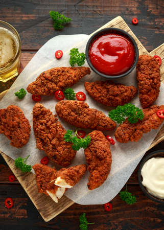 Breaded chicken strips with beer, ketchup and mayonnaise on wooden boardの写真素材