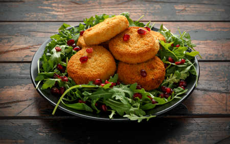 Thai food spicy fish cakes served with pomegranate seeds and wild rocket, arugula salad.